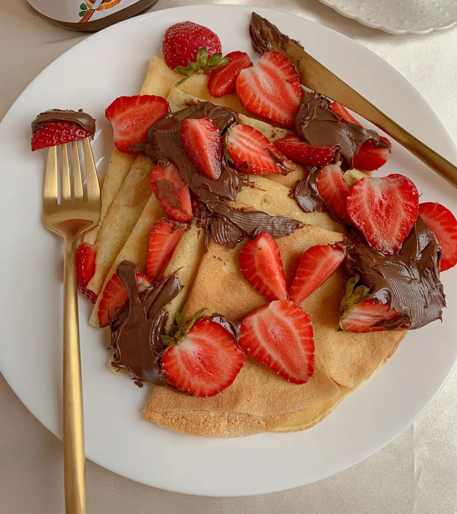 Crepe topped with sliced strawberries and chocolate